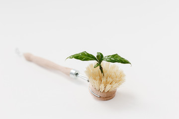 Bamboo dish washing brush with sprout green leaf on white textured background