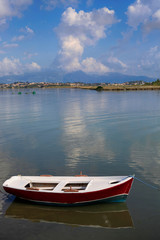 Summer landscape off the coast of Corfu island in Greece with a fishing boat in calm sea water, beautiful cloudy sky and mountains in the background