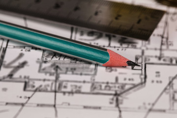 Coal pencil and metal ruler on a technical drawing of an apartment.