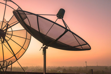 aerial view sunrise on the old satellite dish collapsed on the roof of the tall building.