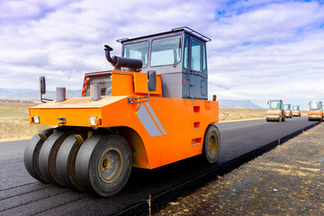 Road roller at road construction site with cloudy blue sky