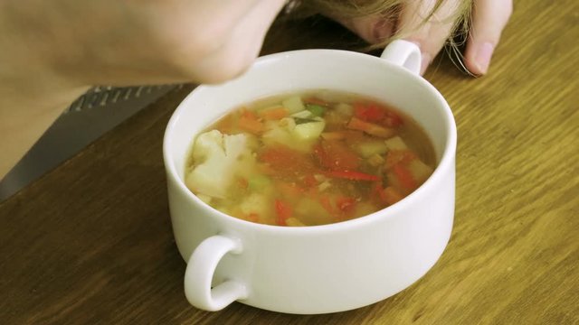 Healthy food. Close-up shot of young blonde woman eating vegetable soup at restaurant. 4K
