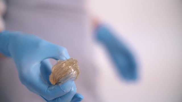 Sugar paste for sugaring in beauty salon. Beautician holds sugar paste with his hands. 