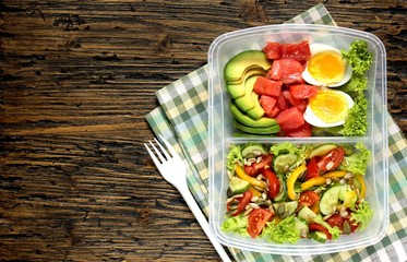 keto diet lunch box - salmon, avocado, egg, salad with tomatoes, sweet pepper, cucumber, pour abundantly with oil, season with sunflower seeds and pumpkin. copy space. top view. 