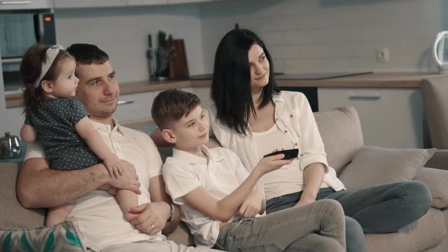 Happy family watching tv at home on couch