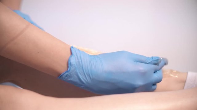 Depilation of legs with sugar paste or sugaring. Master of shugaring process of hair removal with sugar on legs. 