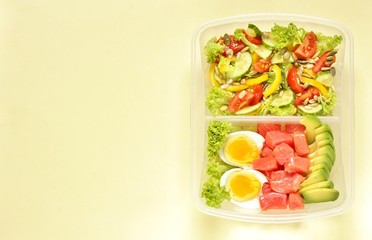 keto diet lunch box - salmon, avocado, egg, salad with tomatoes, sweet pepper, cucumber, pour abundantly with oil, season with sunflower seeds and pumpkin. copy space. top view. 