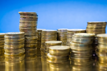 Piles of gold coins on a blue background. Finance, business, money. Hryvnia. Profit. Currency.