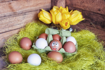 Easter composition with white and brown eggs in box with an egg plastered with a funny face