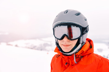 portrait of a skier woman in helmet and ski goggles with foggy mountains background