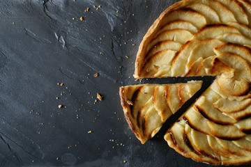 Top view of sliced apple tart on slate with text space
