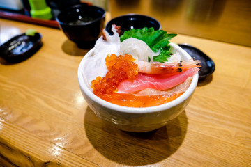 Sashimi served fresh rice bowl  on top salmon,tuna, salmon eggs , slice squid and small shrimp, close up sashimi seafood  in Japanese style with miso soup and wasabi in Japanese restaurant.