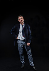 elegant fashionable man in a shirt and coat on standing on a black background