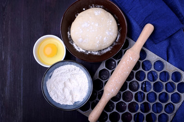 Dough and utensils for making dumplings against the dark background