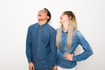 Young couple with glasses posing with arms at hip and laughing