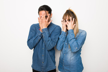Young couple with glasses covering eyes by hands and looking through the fingers