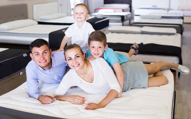 Obraz premium parents with two young sons testing mattress in store