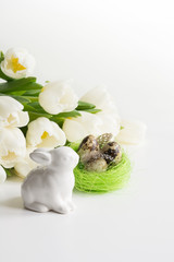 Easter concept. White tulips, nest, eggs on white.