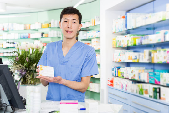 japanese specialist standing near table with cashbox in pharmacy