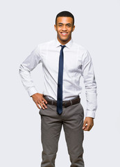Young afro american businessman posing with arms at hip and smiling on isolated background