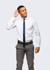 Young afro american businessman thinking an idea while scratching head on isolated background