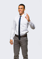 Young afro american businessman showing an ok sign with fingers on isolated background