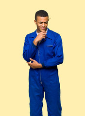 Fototapeta premium Young afro american worker man looking down with the hand on the chin on isolated background