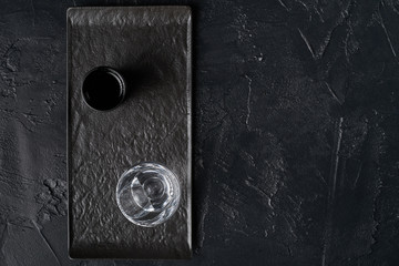 Two glasses of alcoholic beverages on black ceramic plate isolated on black textured background top view