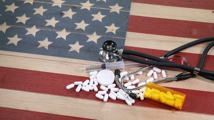 Epidemic drug concept consisting of prescription pain killers with syringe and other medical equipment on wooden United States flag