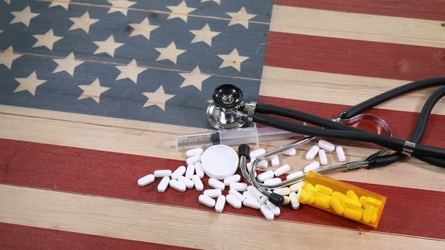 Epidemic drug concept consisting of prescription pain killers with syringe and other medical equipment on wooden United States flag