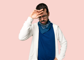 Handsome man with glasses with tired and sick expression on isolated pink background