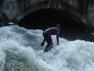 a man in a black wetsuit is in the water under the bridge