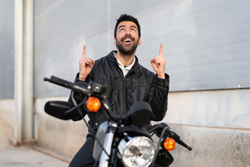 Fototapeta na wymiar Young man on a motorbike pointing up