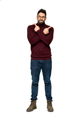 Naklejka premium Full-length shot of Handsome man with glasses pointing to the laterals having doubts on isolated white background