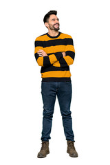 Naklejka premium Full-length shot of Handsome man with striped sweater keeping the arms crossed while smiling on isolated white background
