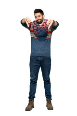 Full-length shot of Hippie man showing thumb down with both hands on isolated white background