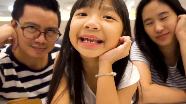 Girls and dad and mother who have good mood are looking at the camera and speak or communicate via tablet or smartphone.