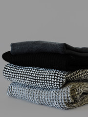 Stack of various sweaters isolated on white background.A stack of knitted sweaters ,the concept of warmth and comfort, hobby , background,closeup
