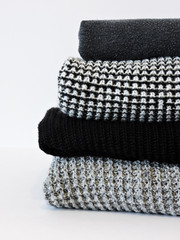 Stack of various sweaters isolated on white background.A stack of knitted sweaters ,the concept of warmth and comfort, hobby , background,closeup