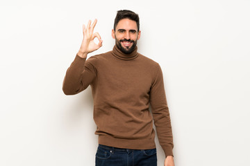 Handsome man over white wall showing an ok sign with fingers