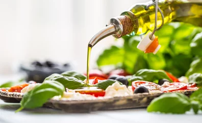 Fototapeten Pouring olive oil on caprese salad. Healthy italian or mediterranean meal © weyo