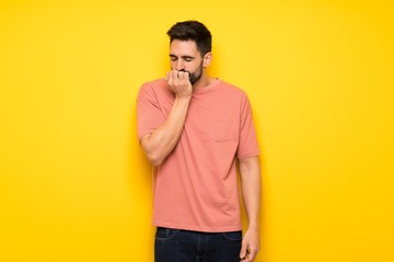 Handsome man over yellow wall having doubts