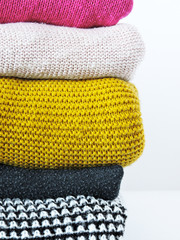 Stack of various sweaters isolated on white background.A stack of knitted sweaters ,the concept of warmth and comfort, hobby , background,closeup