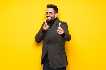 Handsome man with glasses pointing to the front and smiling