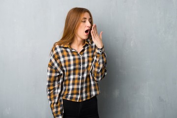 Fototapeta premium Young redhead girl over grunge wall yawning and covering wide open mouth with hand