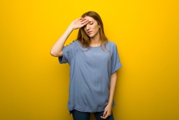 Young redhead girl over yellow wall background with tired and sick expression