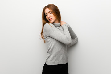 Redhead girl over white wall suffering from pain in shoulder for having made an effort