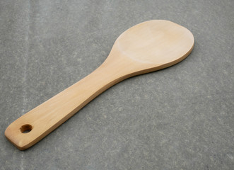 Wooden spoon on grey background.