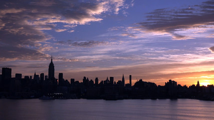 east river and New York City Manhattan midtown silhouette panorama at sunset with skyscrapers