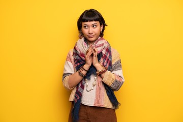 Young hippie woman over yellow wall scheming something